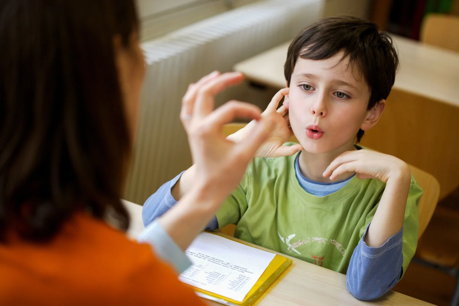Child using an augmentative communication board with an adult